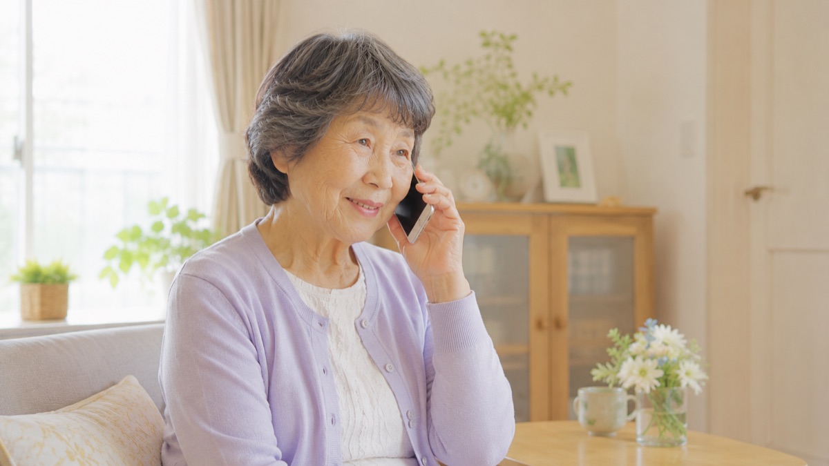 自宅で電話を手に穏やかに相談している高齢の女性